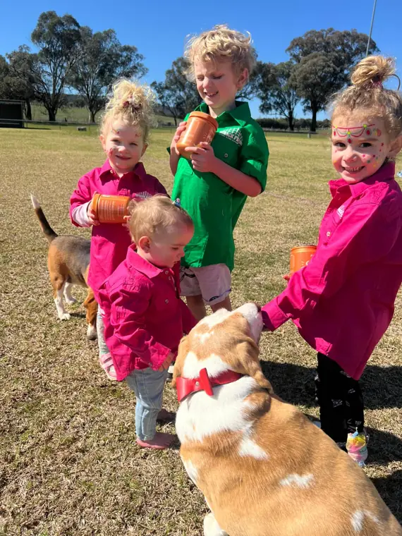 Kids giving a beagle a Bestie Bites chew