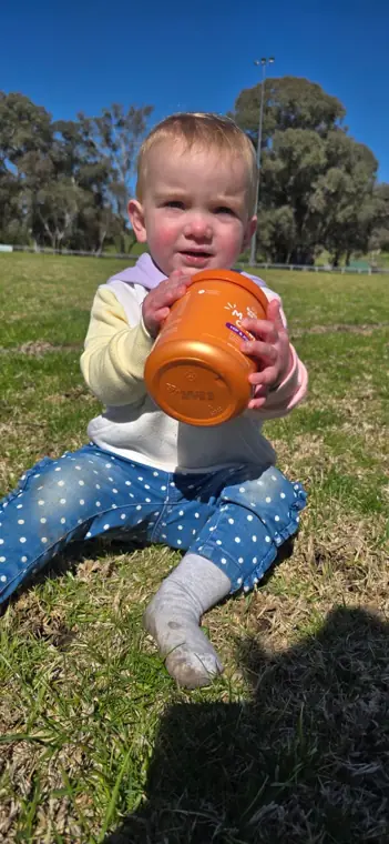 Toddler holding a jar of Bestie Bites on the grass